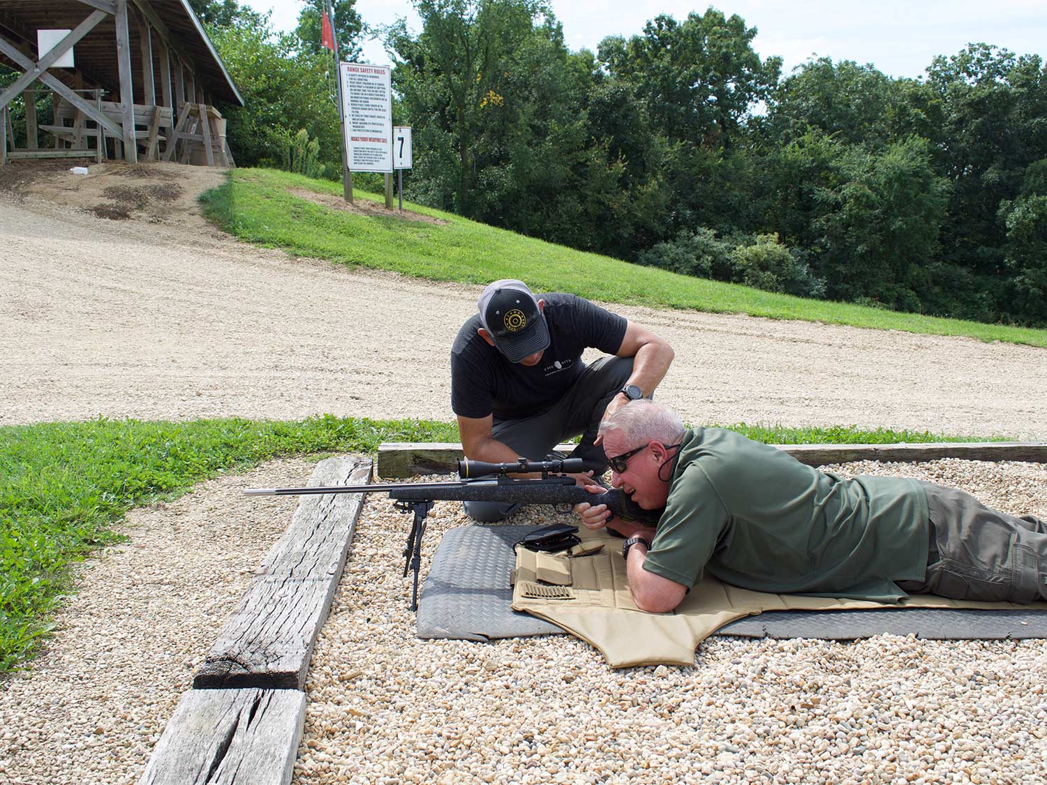 Two men checking scopes on a rifle.