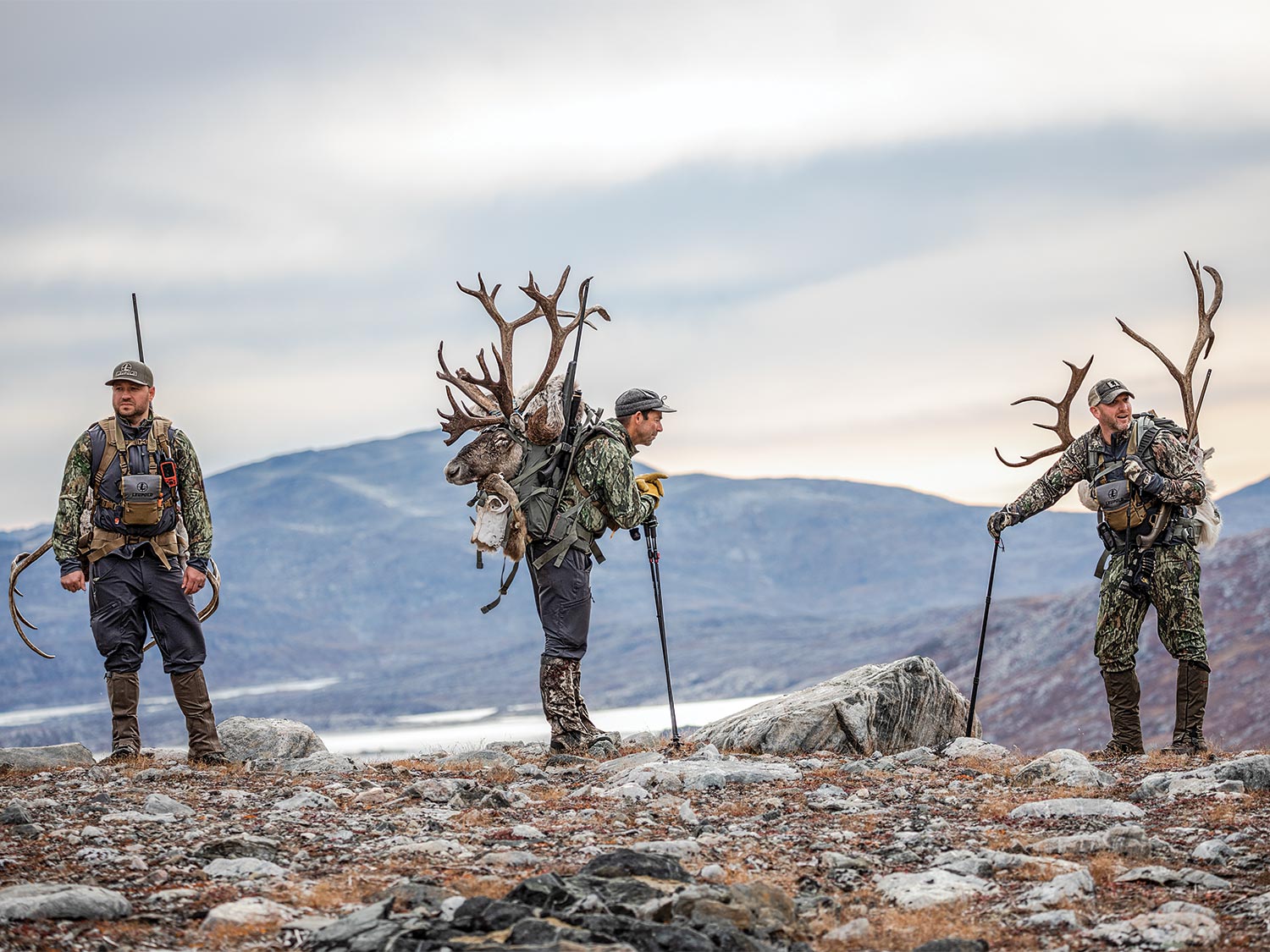 A trio of caribou hunters waiting on a hillside.