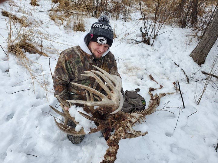 Hunter holding a large set of nontypical deer antlers and skeleton.