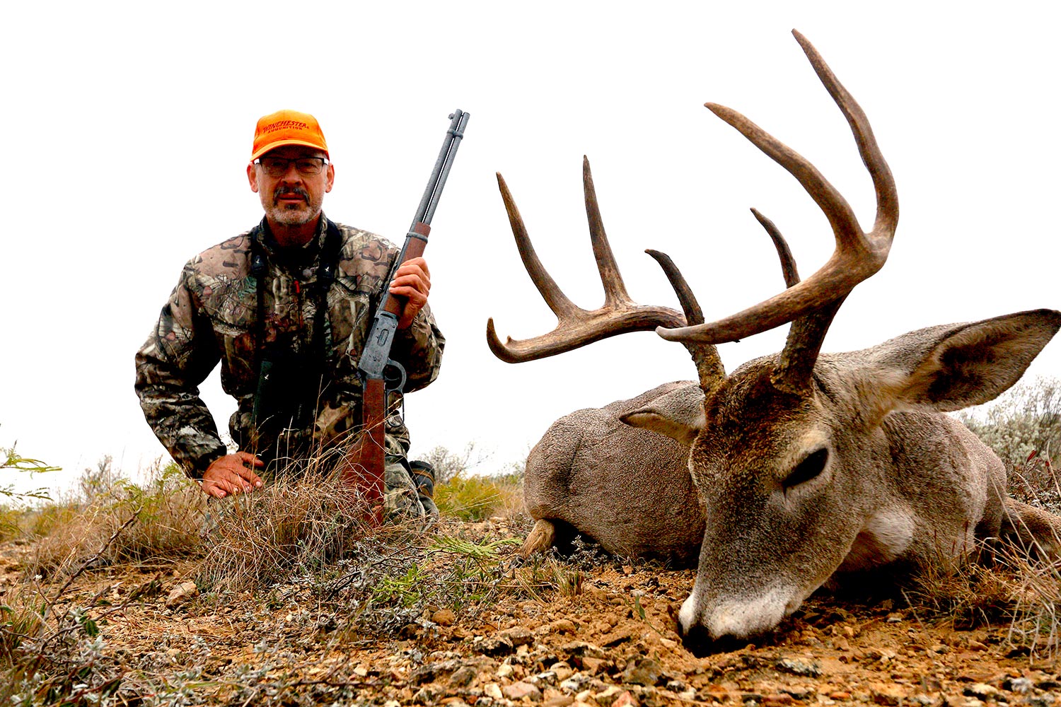 Hunter with a buck and lever-action rifle.