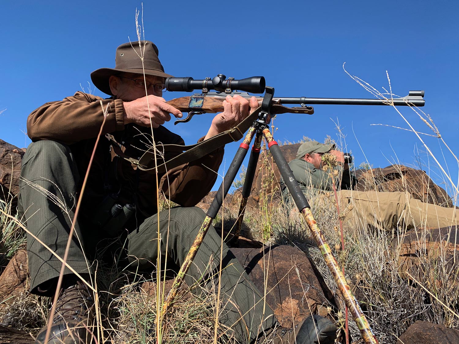 Hunter aiming a rifle using a tripod.