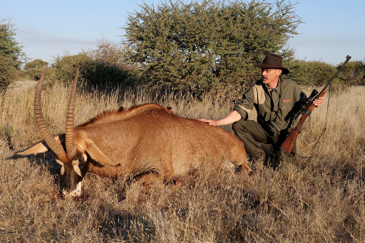 Hunter kneeling beside a large South African roan.