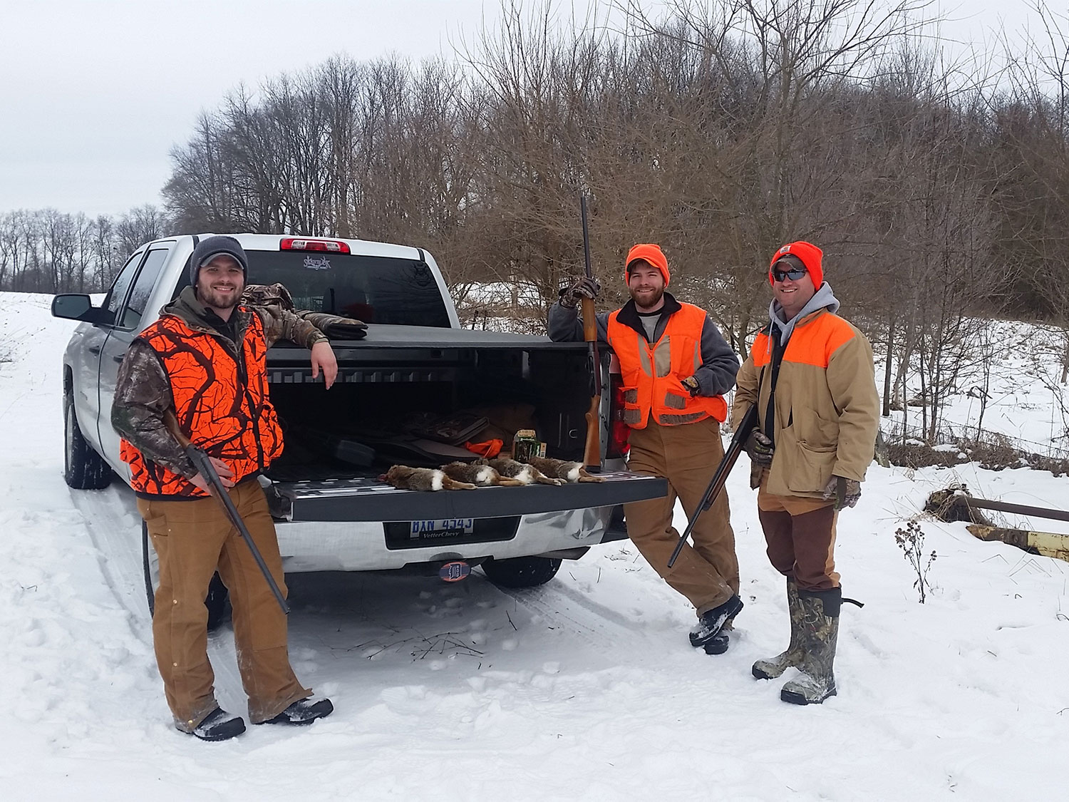 Hunters standing by a truck in the snow.