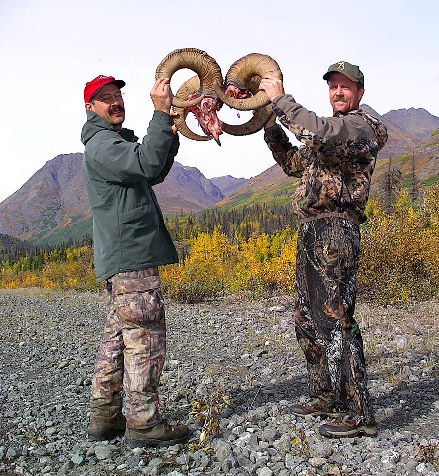 Two hunters holding up ram horns.