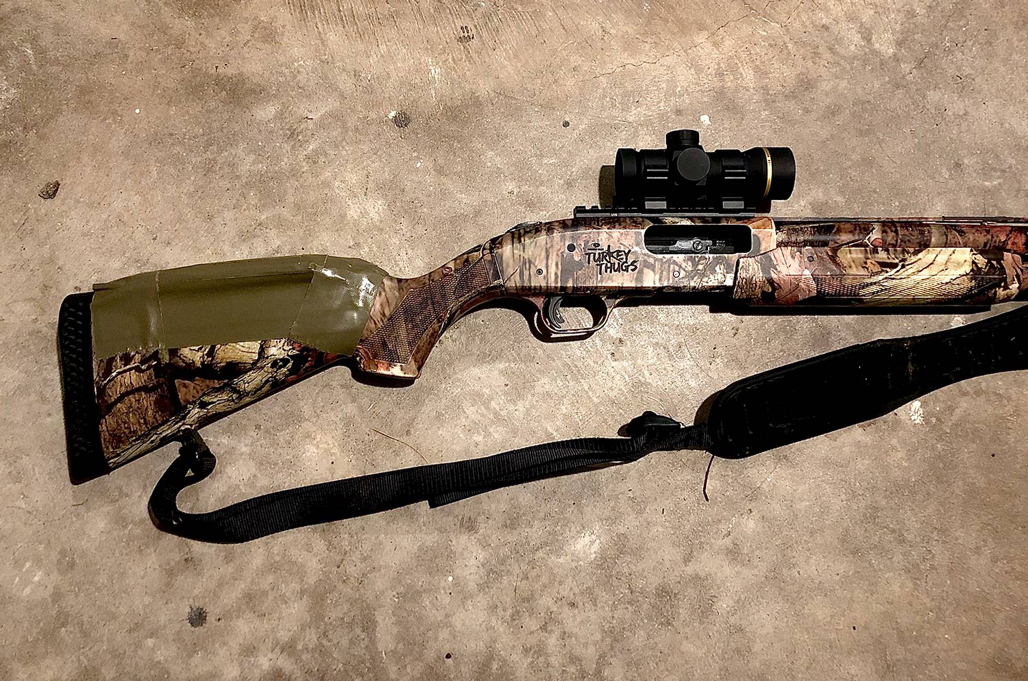 A shotgun with a scope and sling attached.