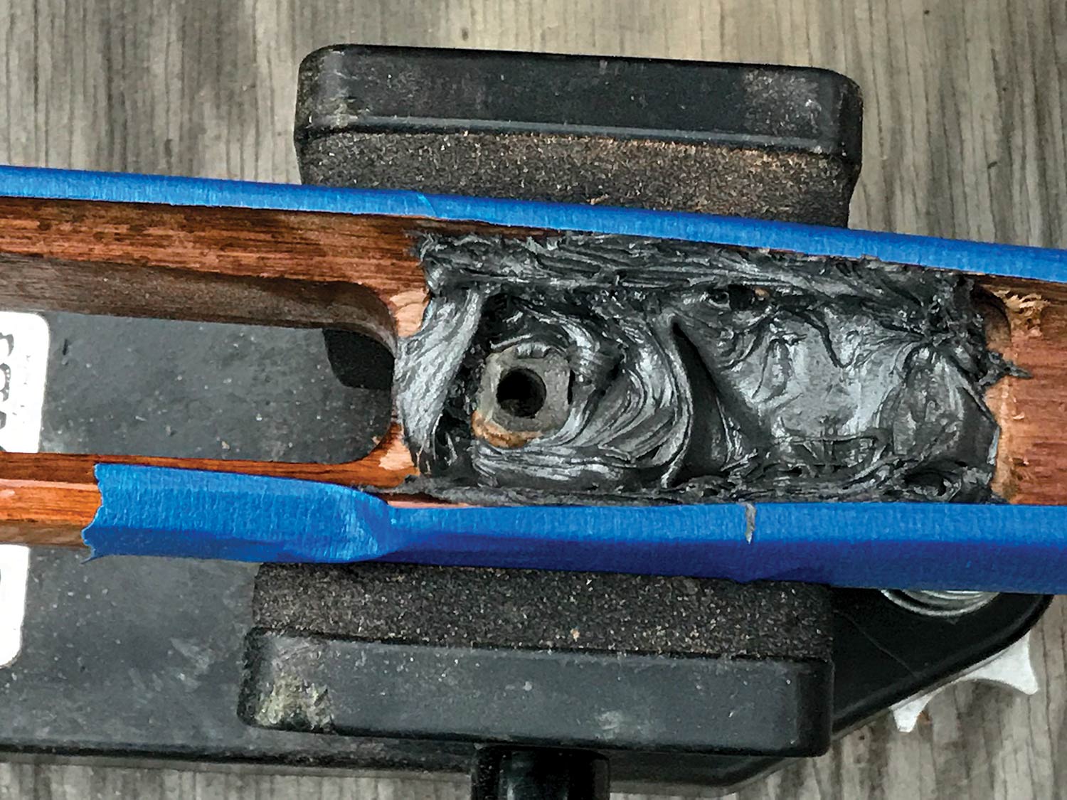 A rifle stock wrapped in blue tape.