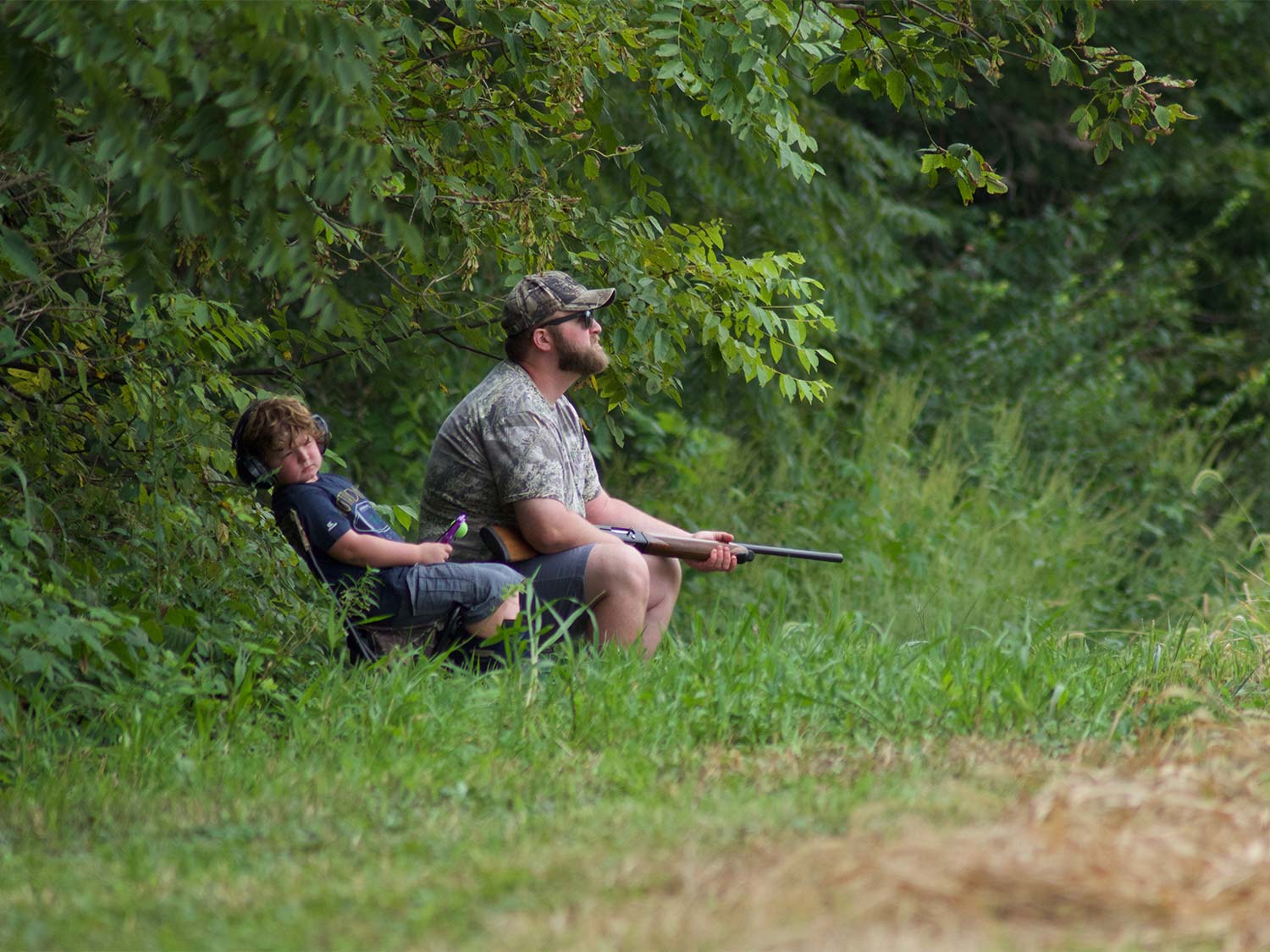 A man and son hunting doves in a field.