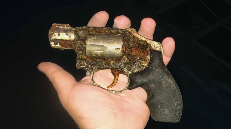 A rusty revolver located in a river.