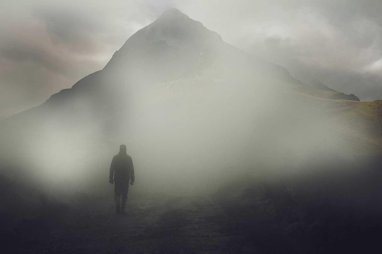 Hiker in a dense fog near a mountain.