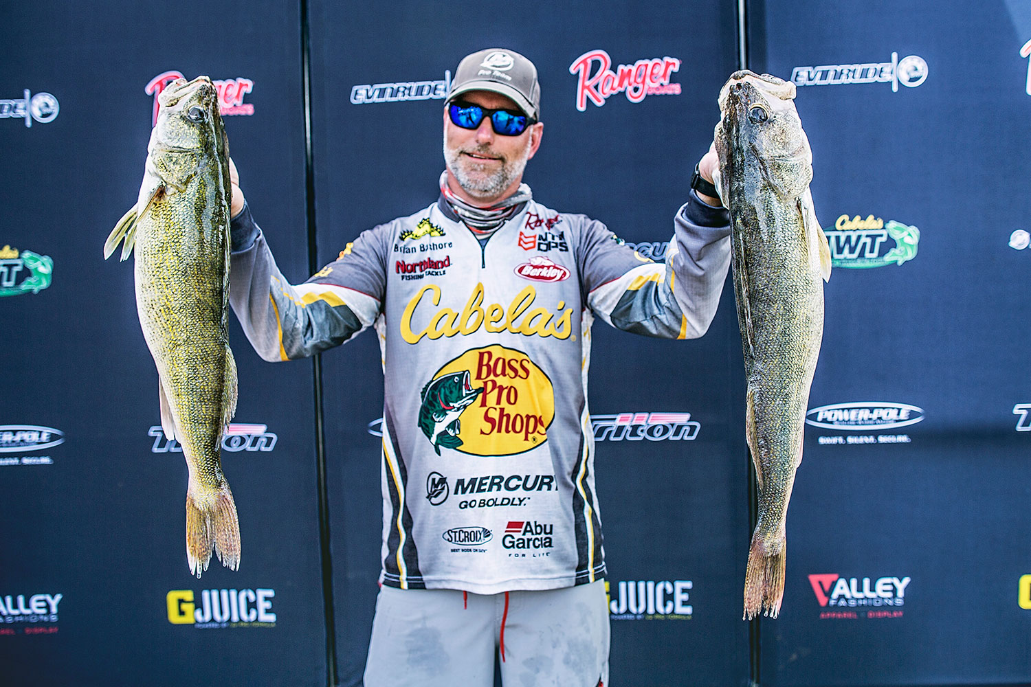 Brian Bashore holds up two walleye at a fishing tournament.