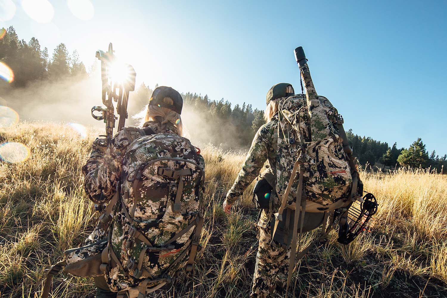 Two hunters scouting through an open field.