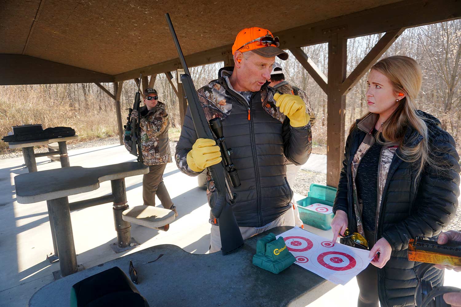 A hunter mentoring another hunter at a shooting range.