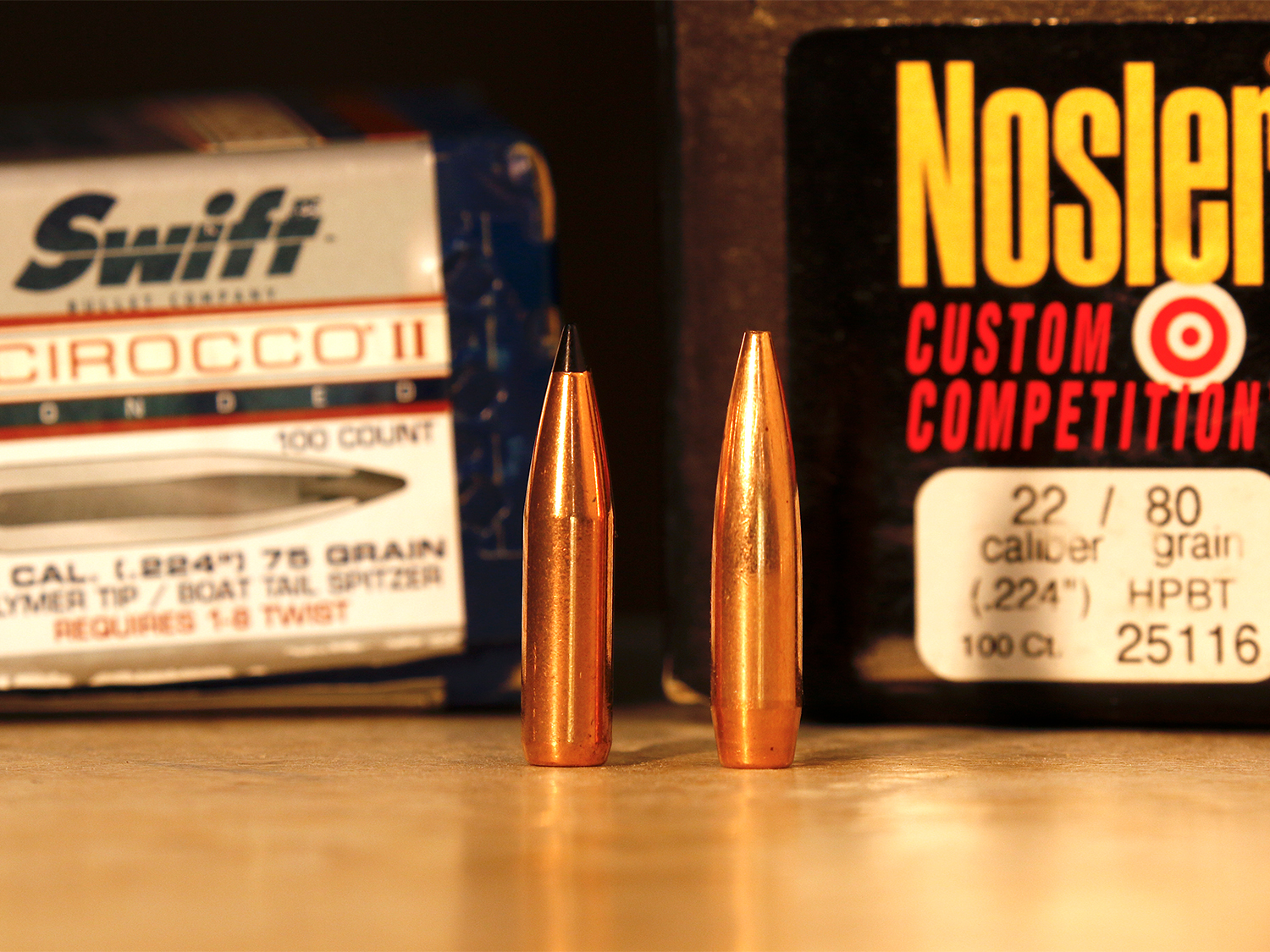 Two different rifle bullets side by side with manufacturing boxes.