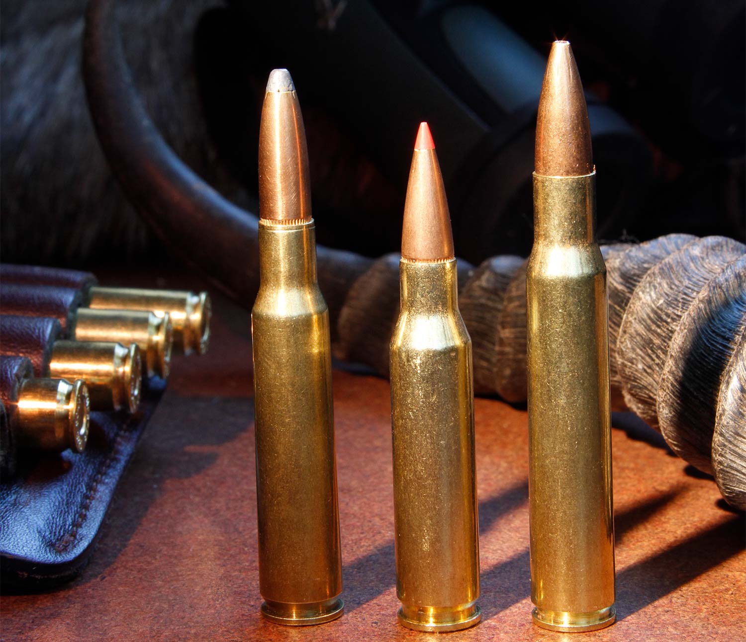 Three rifle cartridges standing up on a table.