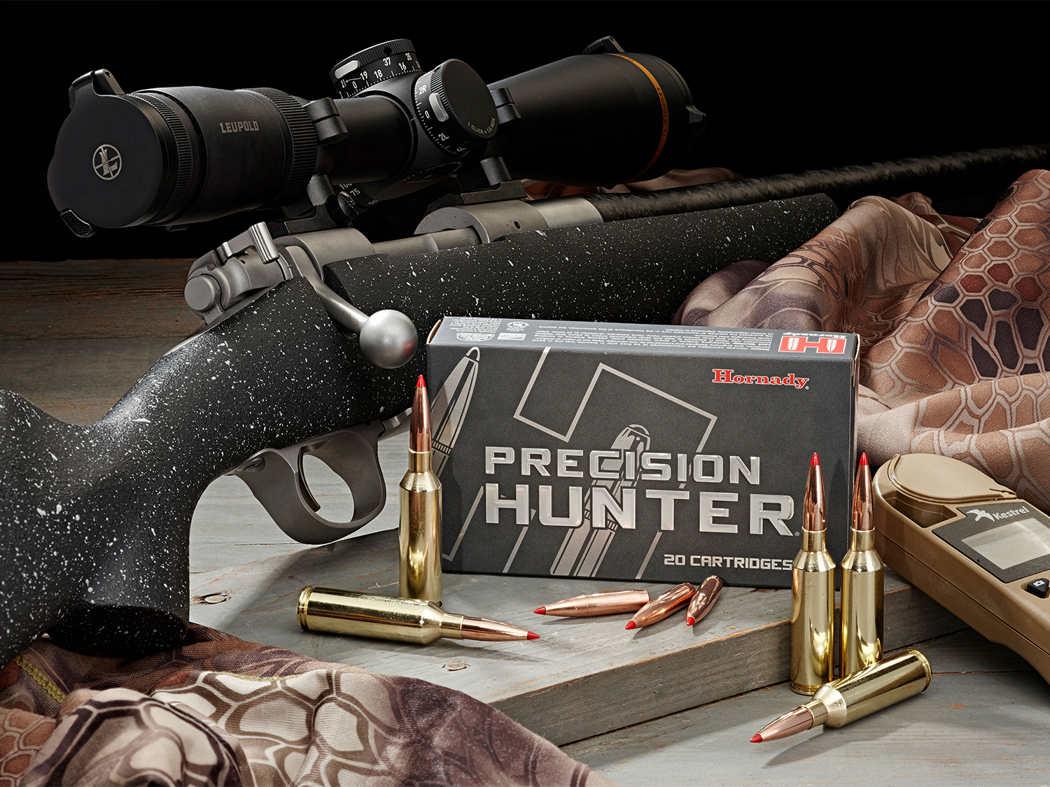 A box of Hornady rifle ammo next to a bolt-action rifle.