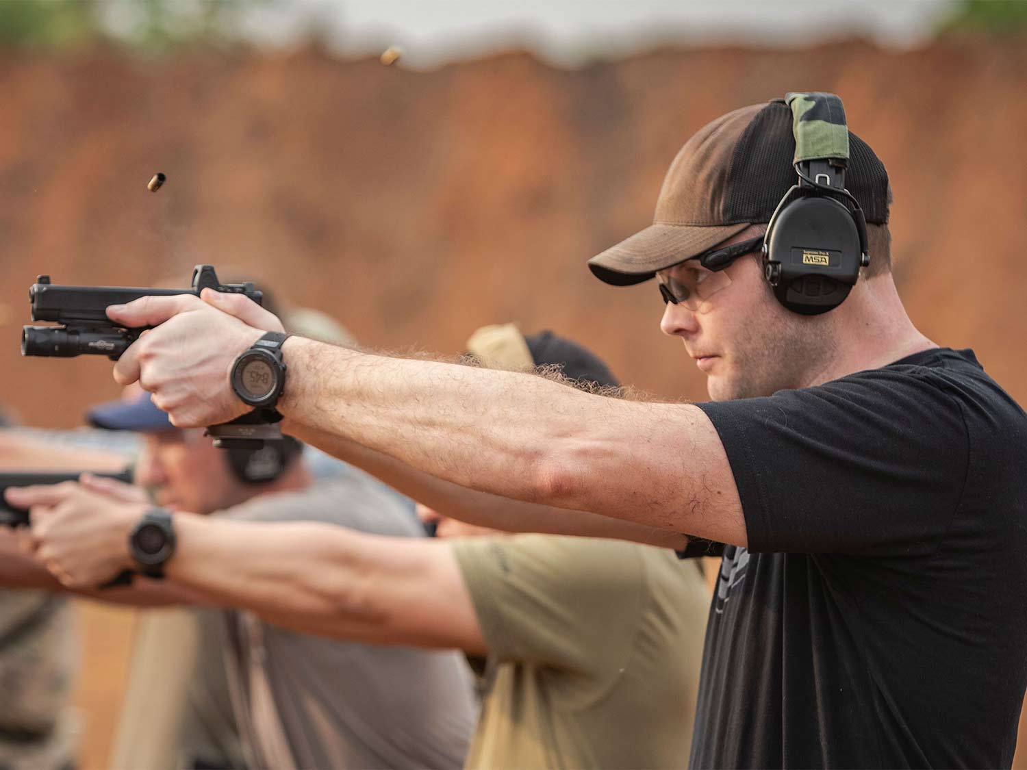 A man aiming a handgun at a shooting range.