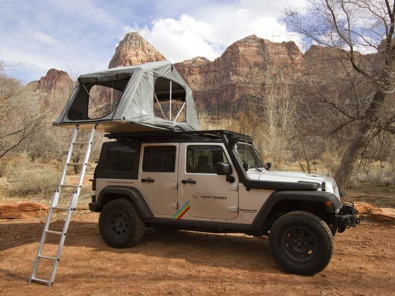A camping tent on the hood of a white jeep.