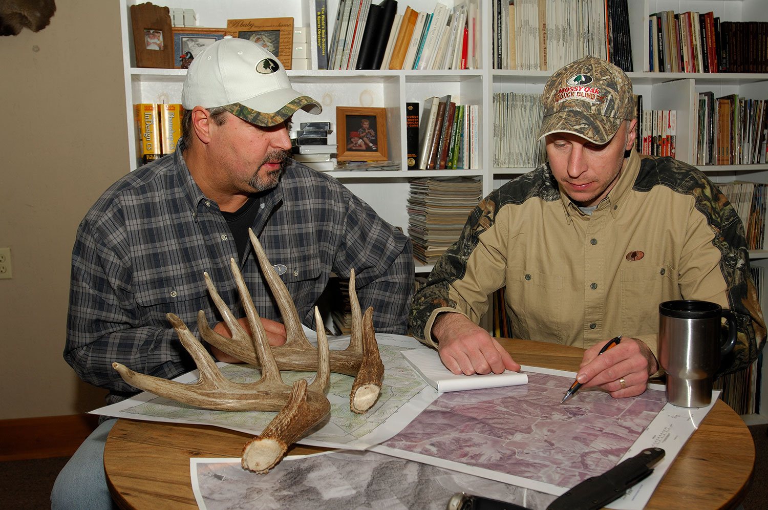 Two hunters look over maps for scouting deer.
