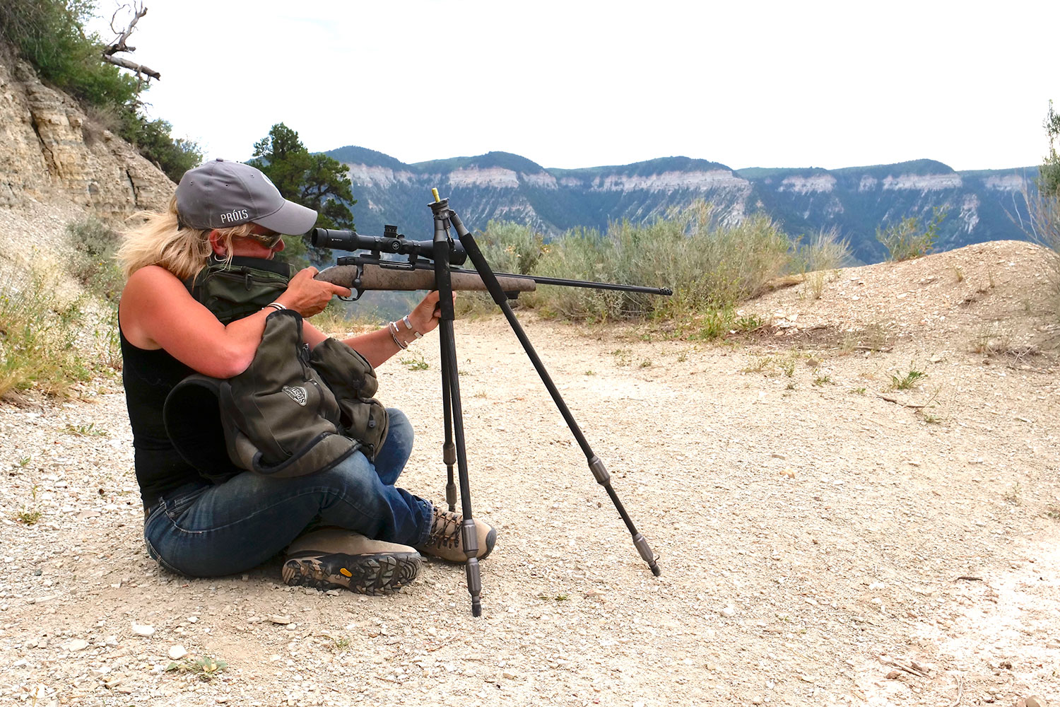 A woman using a tripod to aim a rifle.