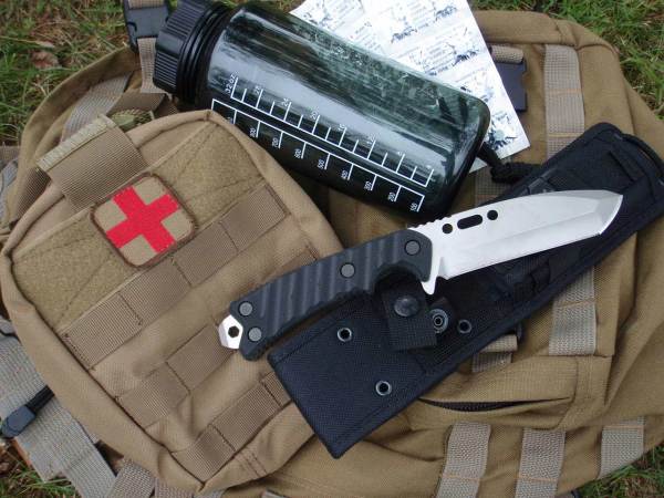 A knife and a water bottle on a survival backpack.