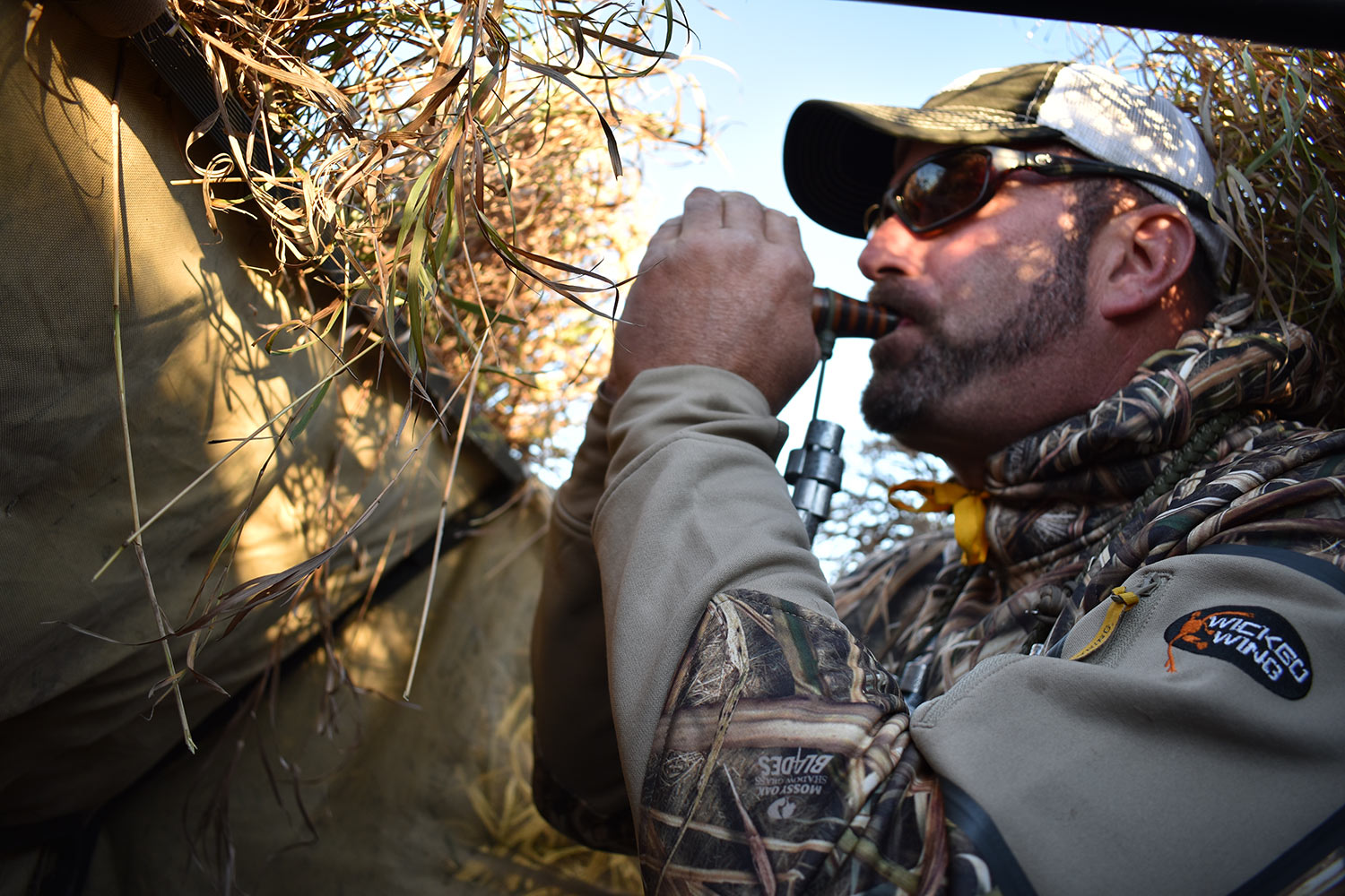 A hunter using a bird call in a hunting blind.