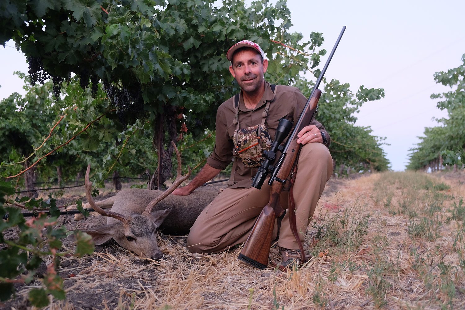 Andrew McKean with a blacktail deer in a hillside.