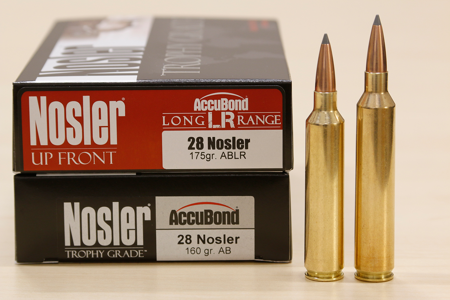 A box of Nosler rifle ammuniton on a table two ammo cartridges standing beside it.