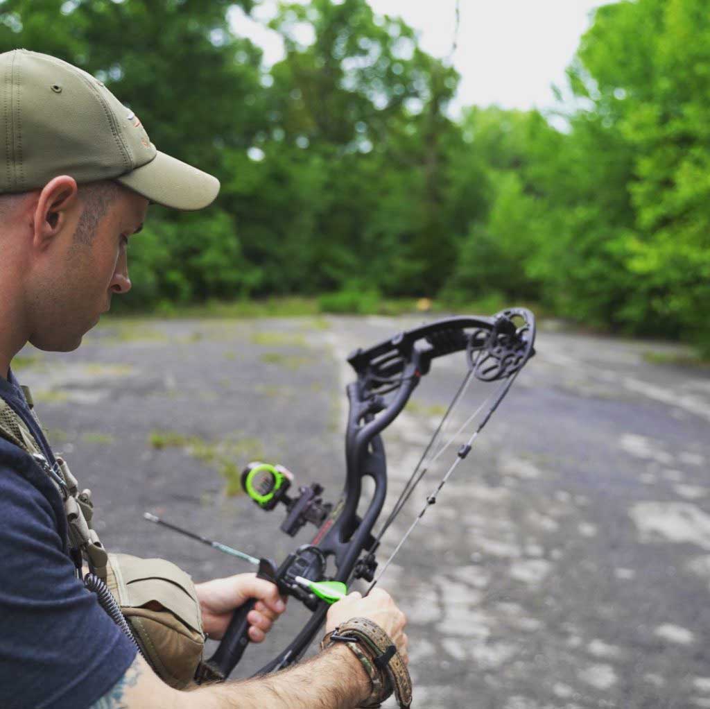 A hunter practicing bowhunting in an open wooded area.