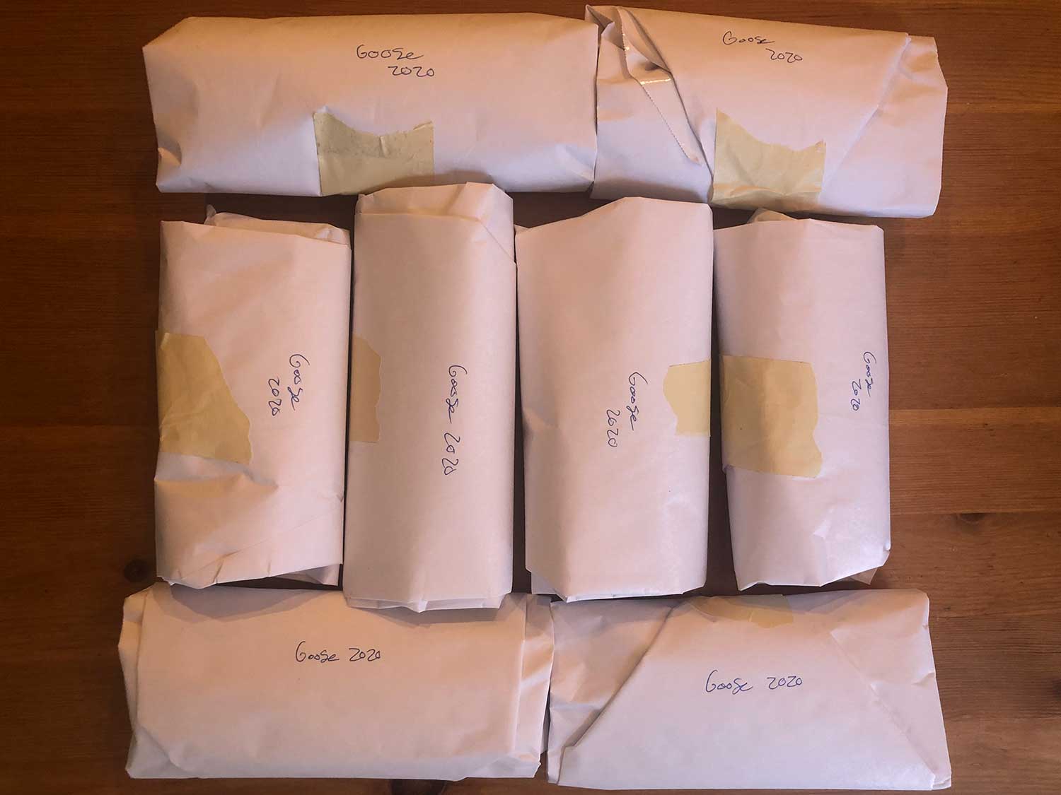 8 packages of goose meat wrapped in butcher paper on a table.
