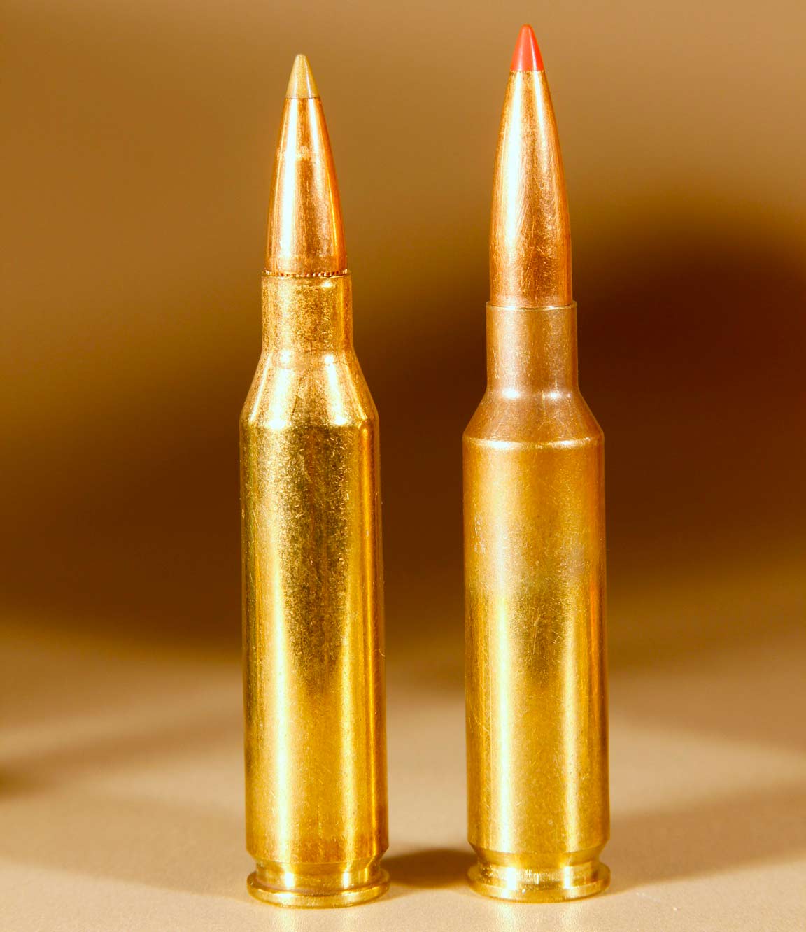 Two rifle cartridges standing on end on a table.