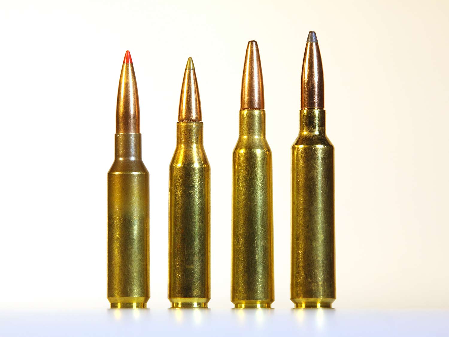 Four rifle cartridges standing on end on a table.