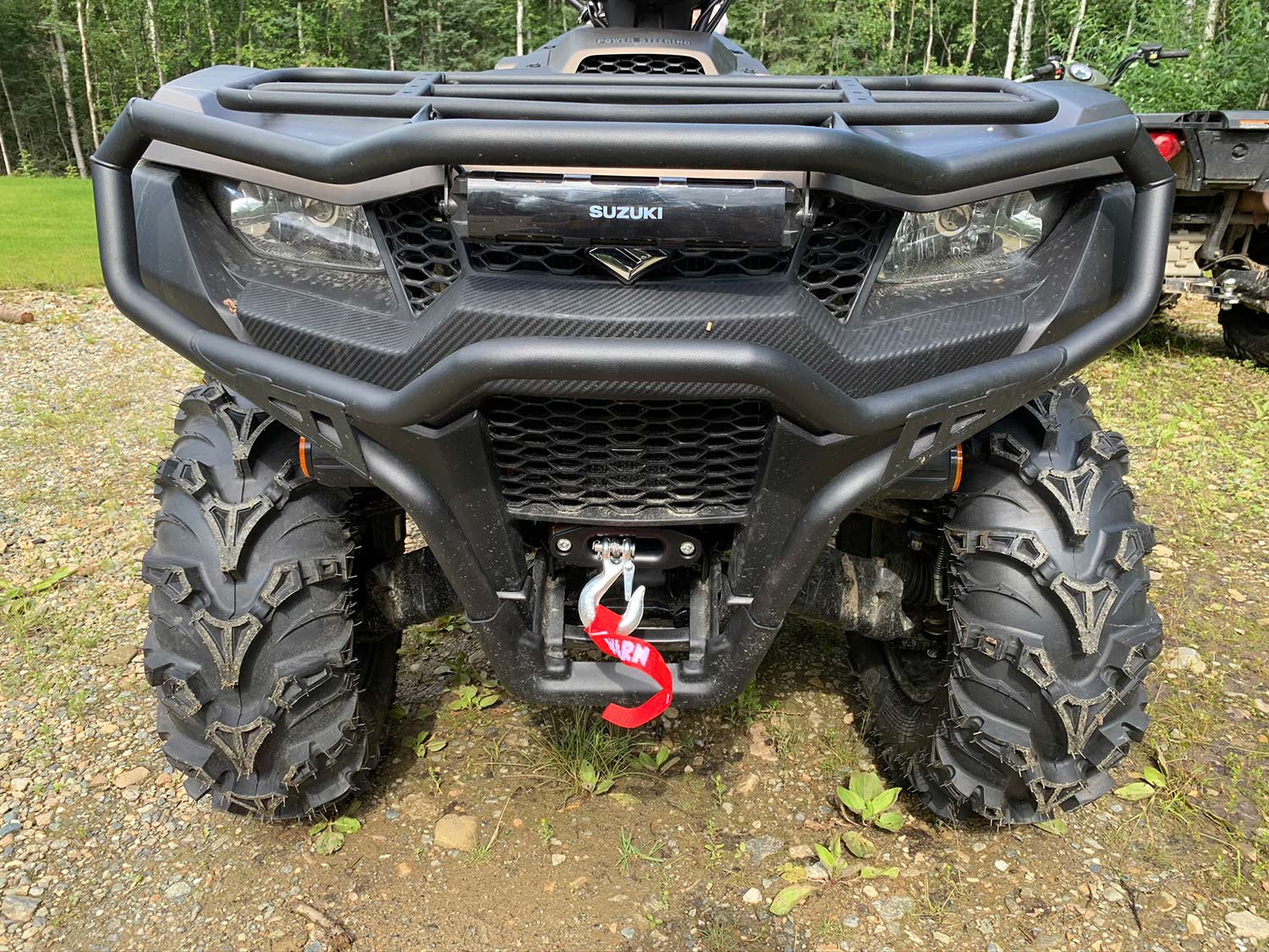 The front of a Suzuki four-wheeler ATV equipped with bumpers and a winch.