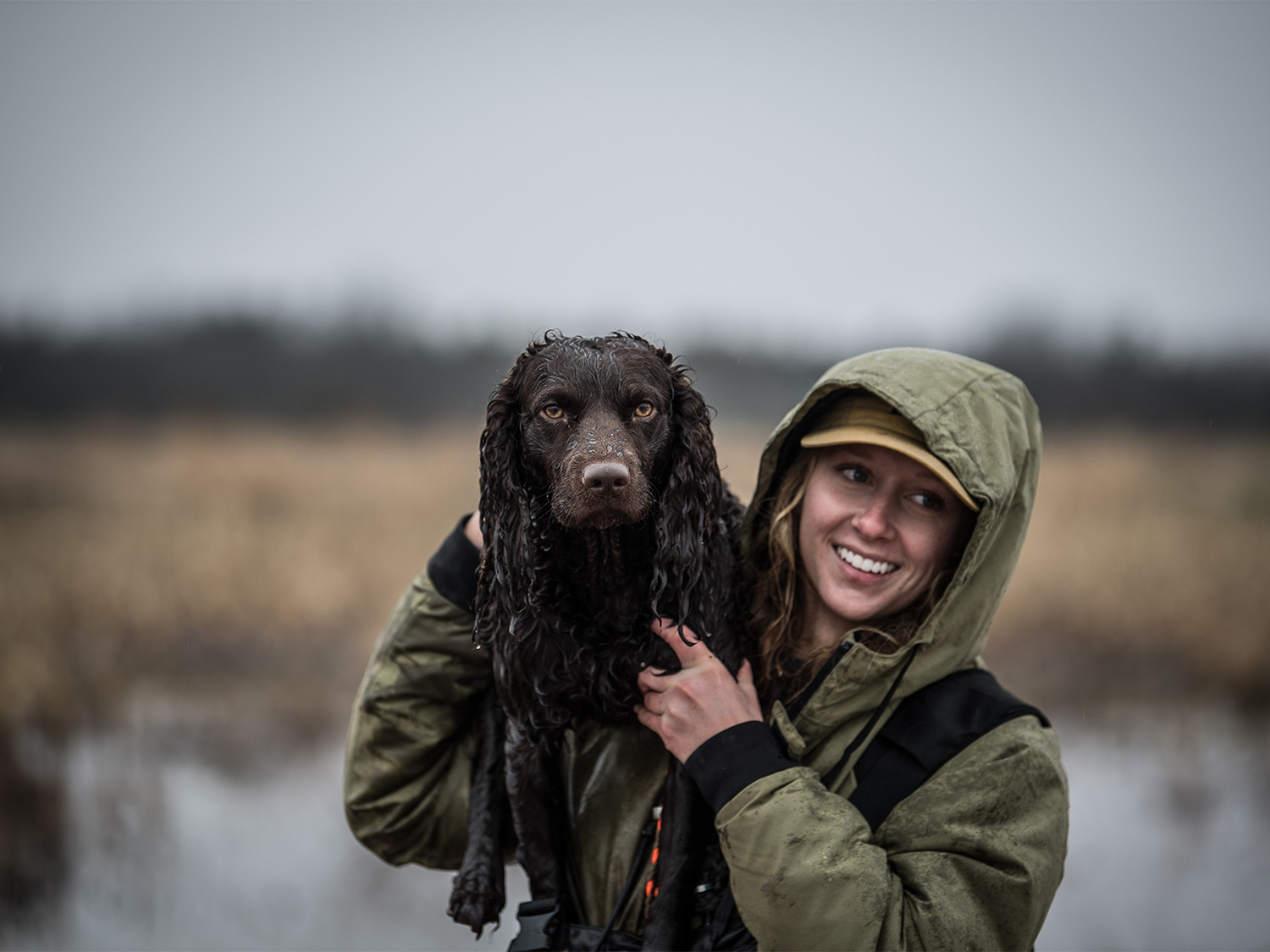 A woman hunter holding up a hunting dog.