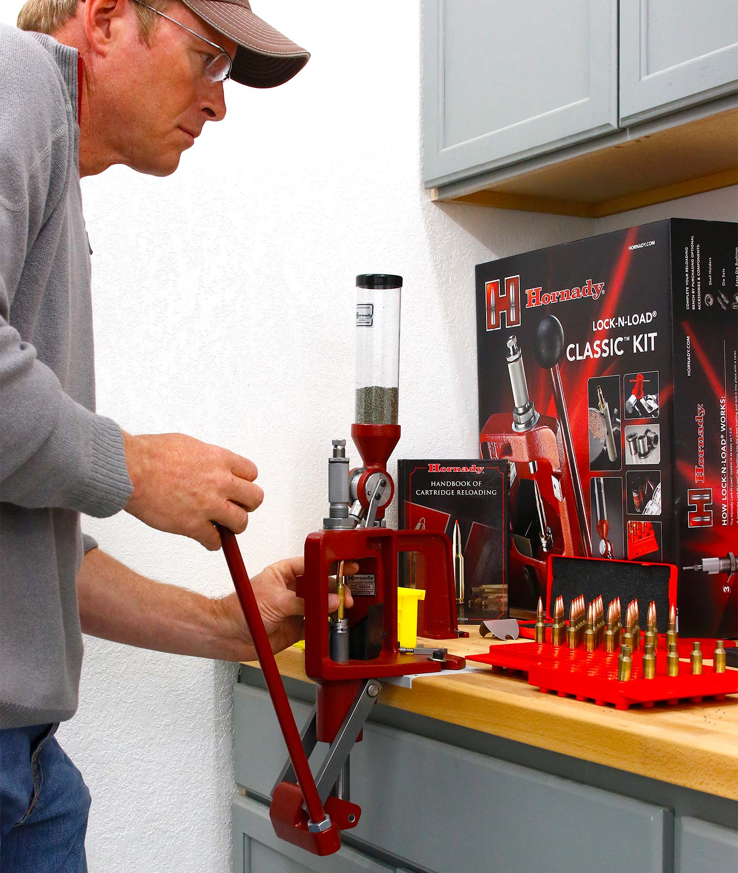 A man operates a custom handloading machine designed for dropping gunpowder into small cyclinders of rifle ammunition cartridges.