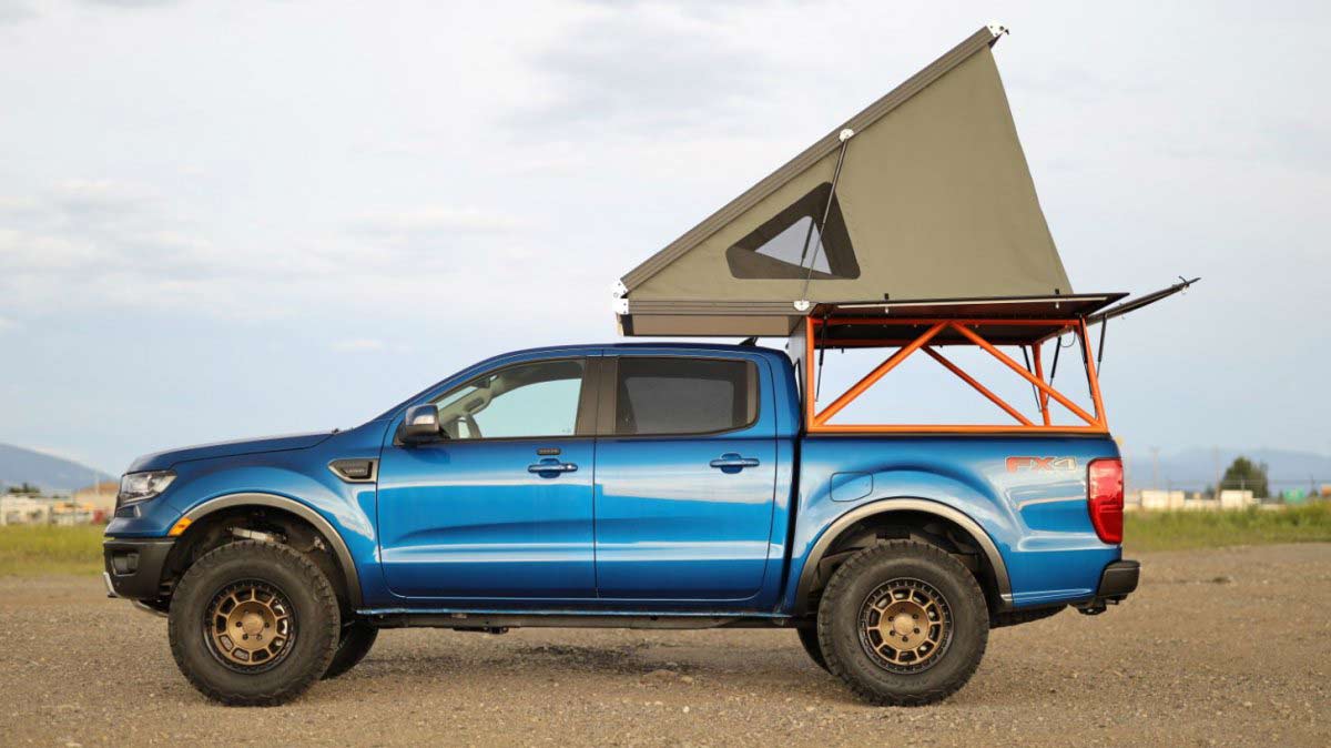 A blue Ford pickup truck with a truck-bed mounted camping tent.