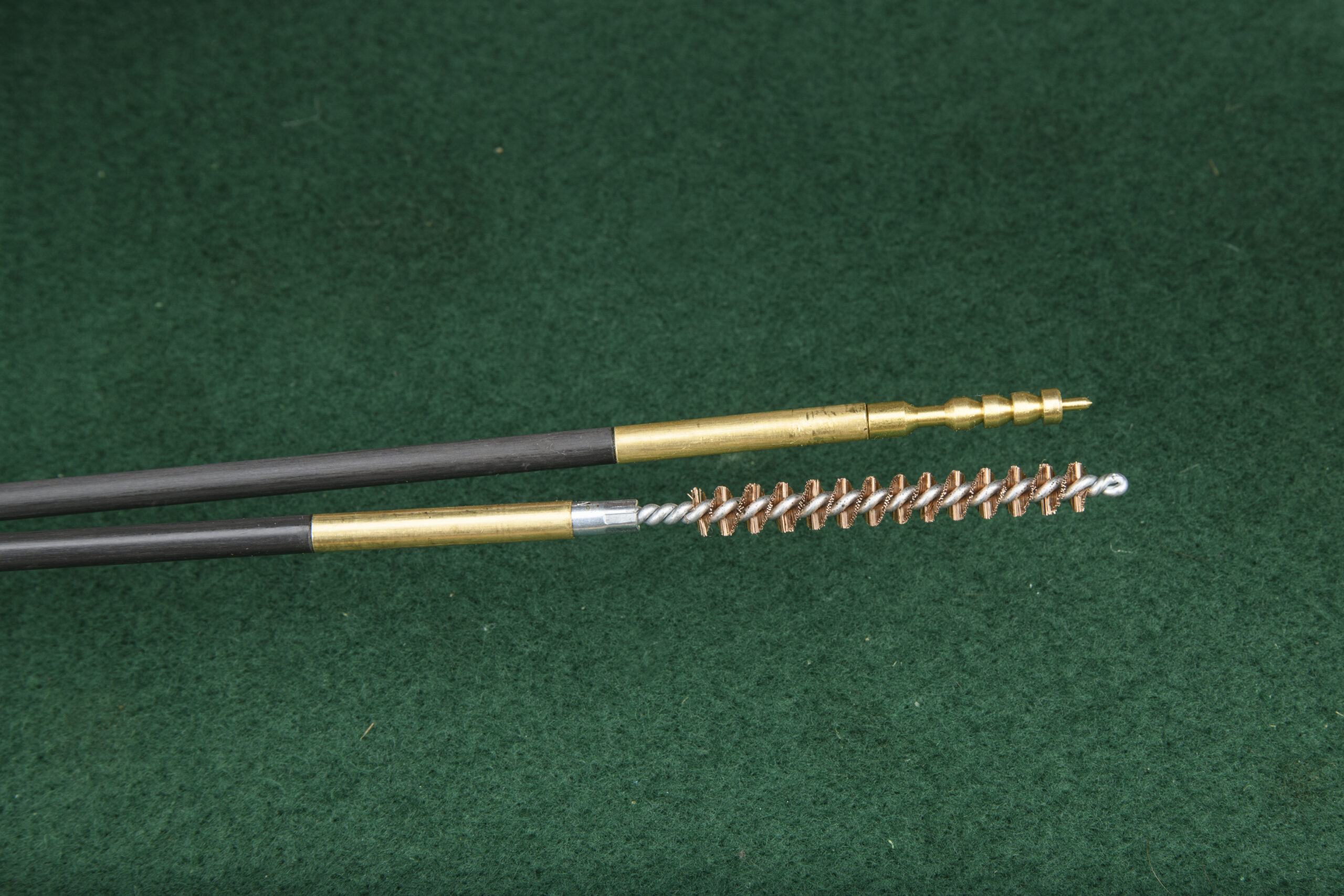 Bronze brushes and jags for cleaning a rifle, on a green felt background.