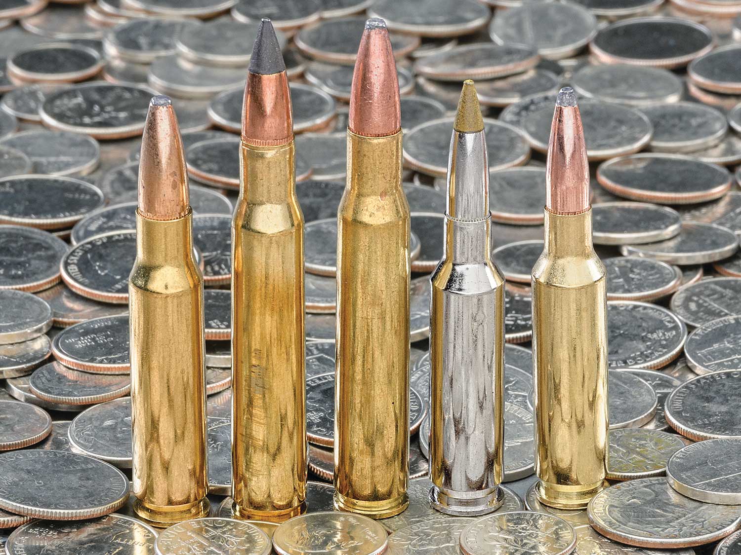 A lineup of deer hunting cartridges on a pile of quarters.