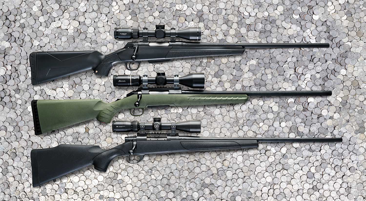 A lineup of three rifles with scopes on a bed of quarters.