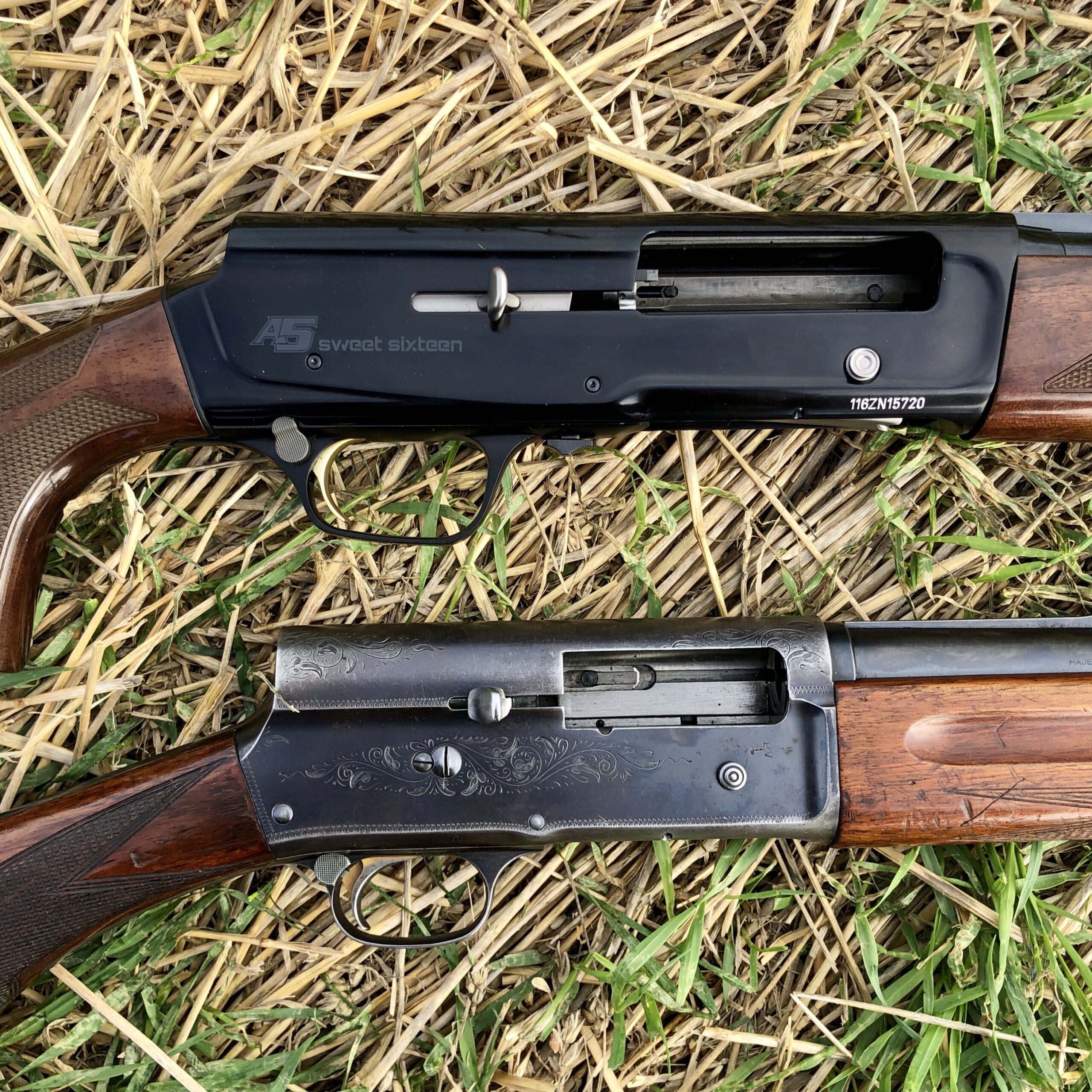 A new and an old wood-stocked semi-auto shotguns on a grass background.