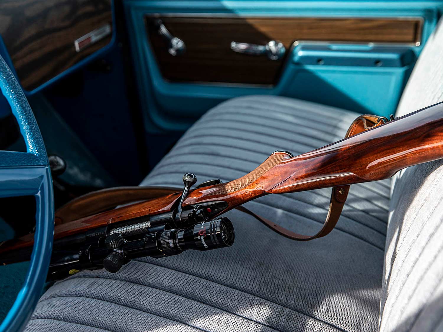 A hunting rifle is placed in the seat of a truck.