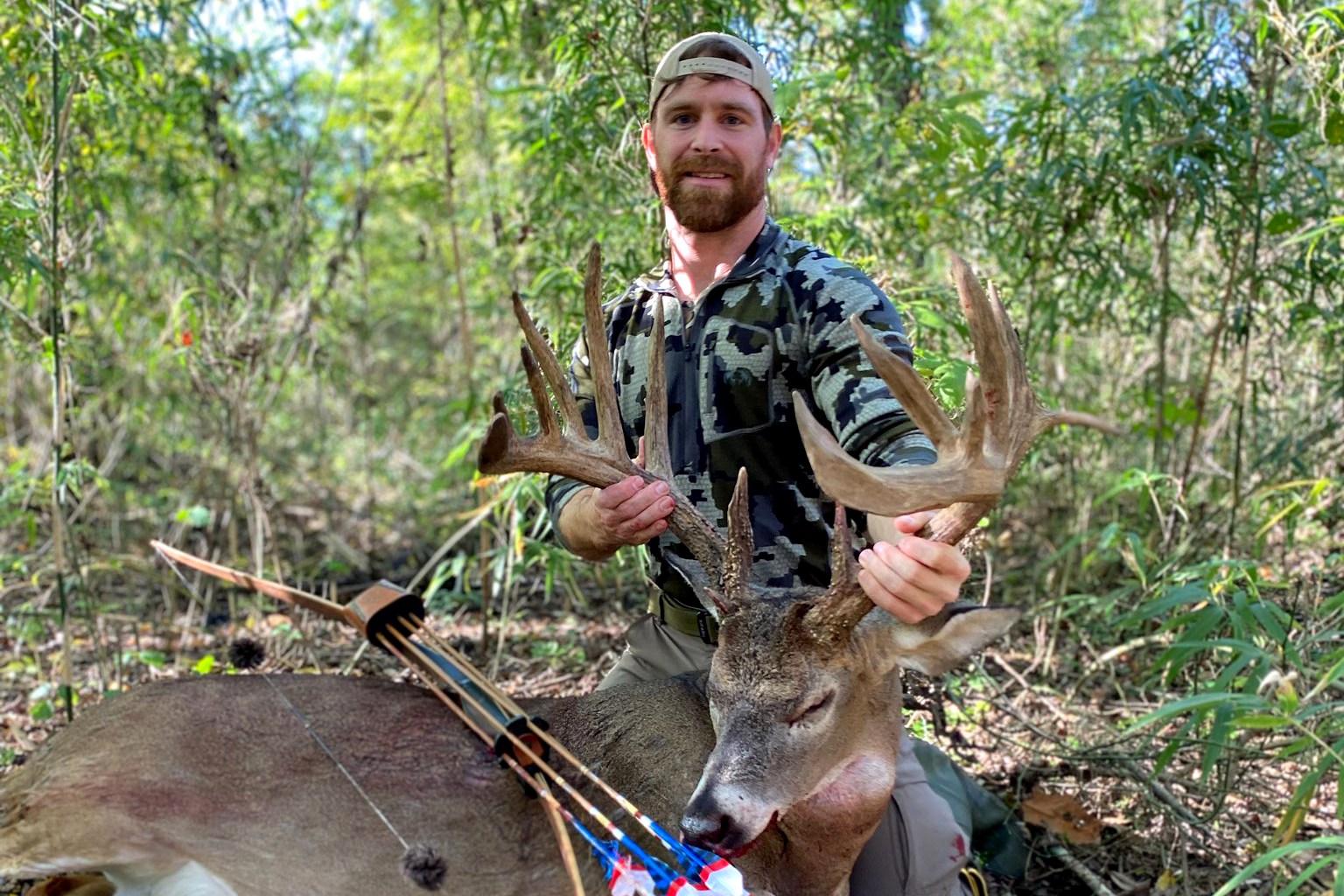 A bowhunter holds the antlers of his archery whitetail buck.