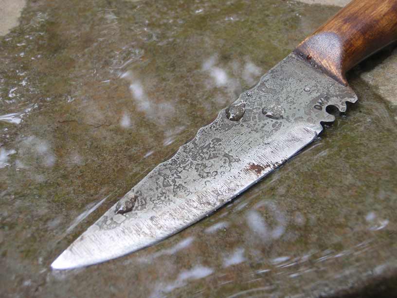 knife being sharpened against a smooth, wet rock.