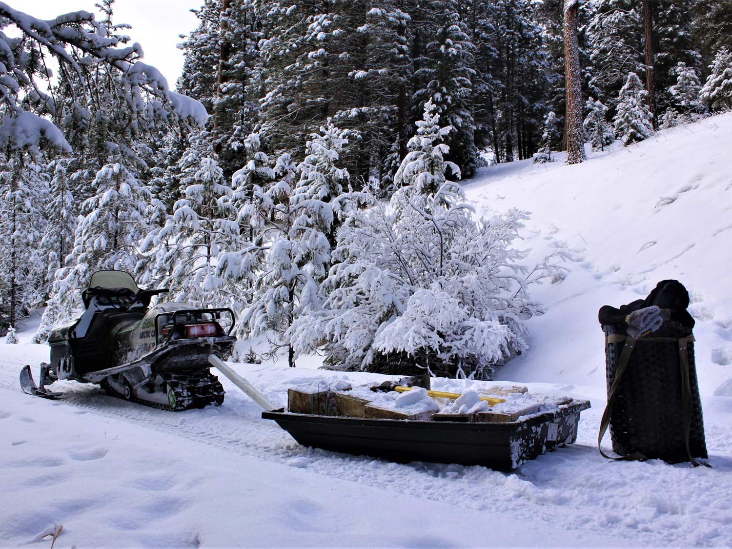 A snowmobile attached to a hunting sled and gear.