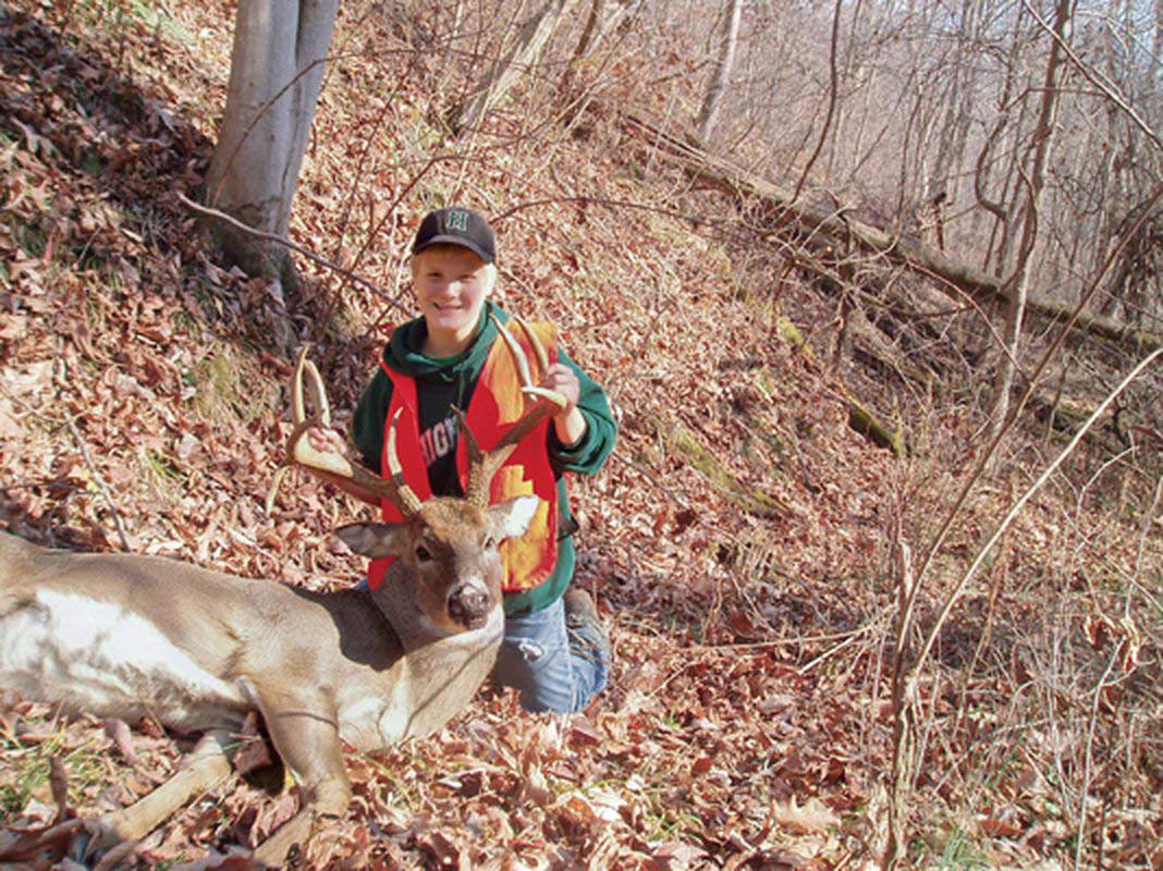 A hunter kneels next to the whitetail deer.