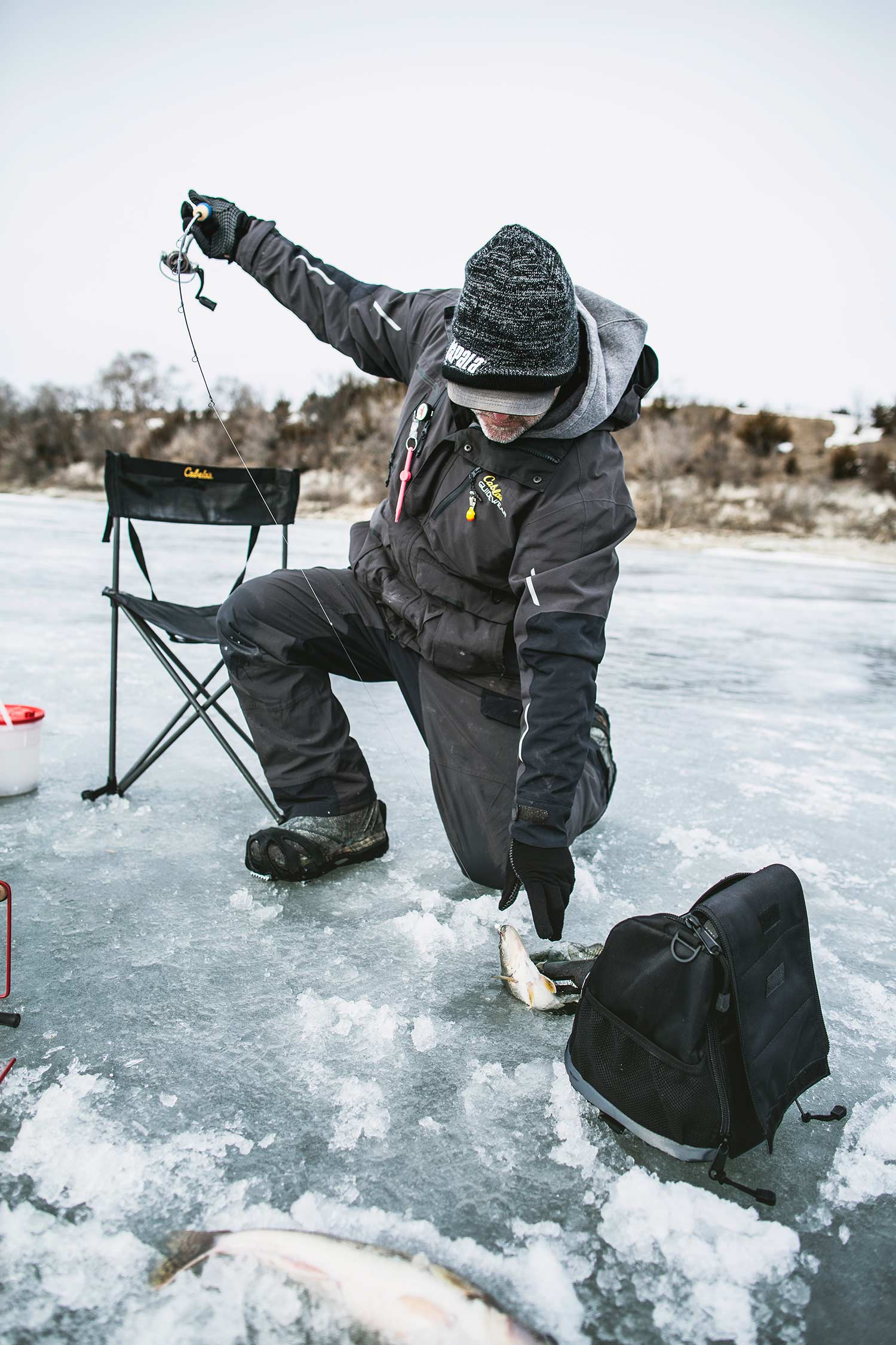 An angler pulls a walleye from an ice fishing hole.