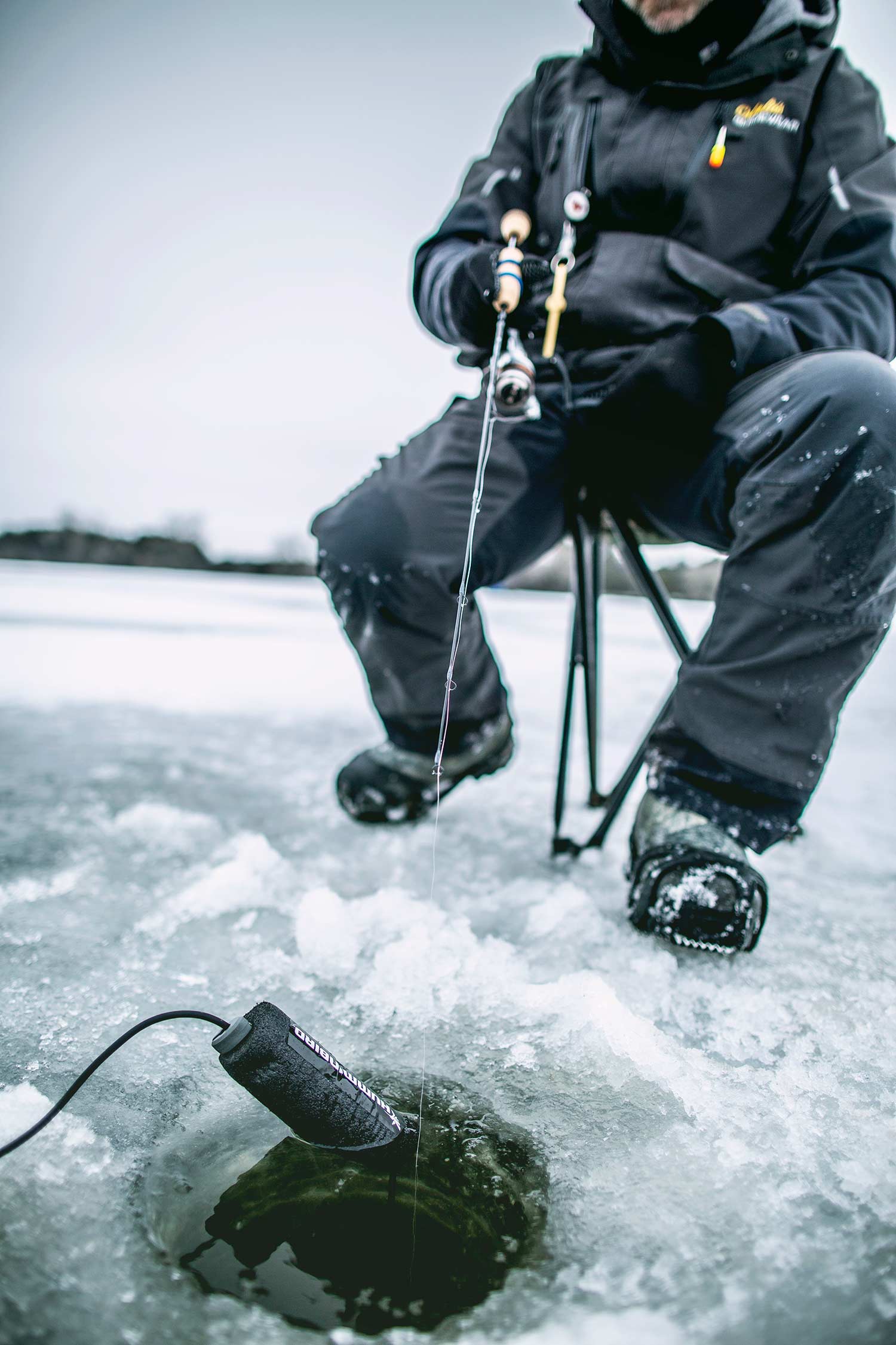 An angler fishes in an ice fishing hole.