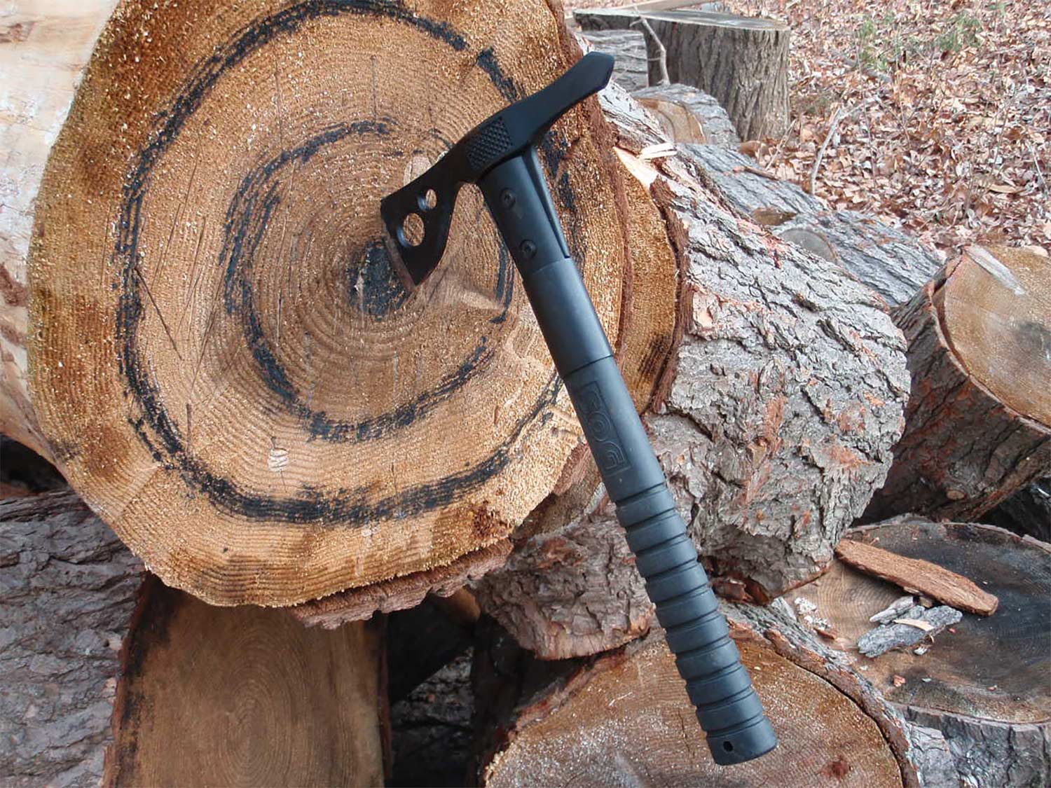 A tactical throwing axe stuck in a tree stump.