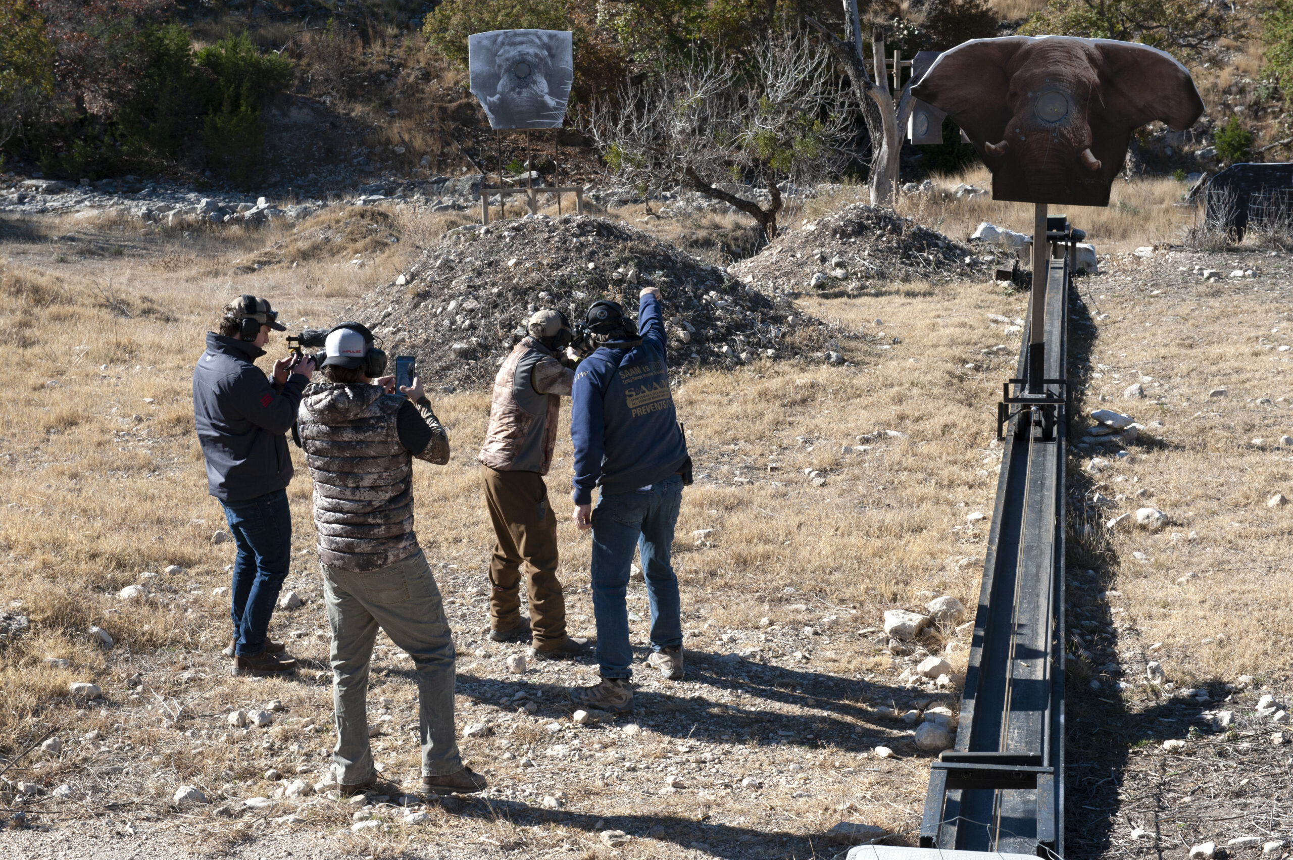 A hunter practices on a charging elephant target with an instructor and two videographers.