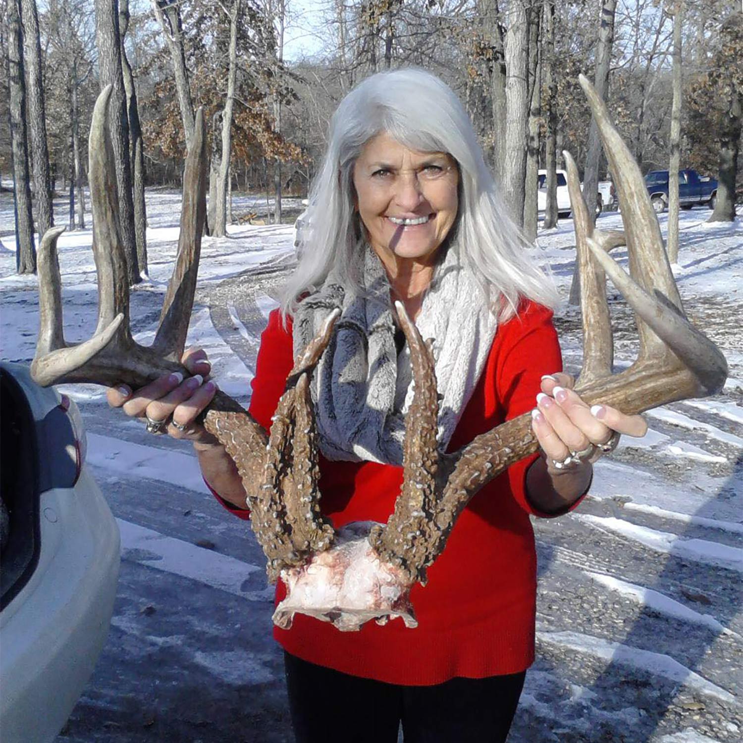 A woman holds a pair of whitetail deer antlers.
