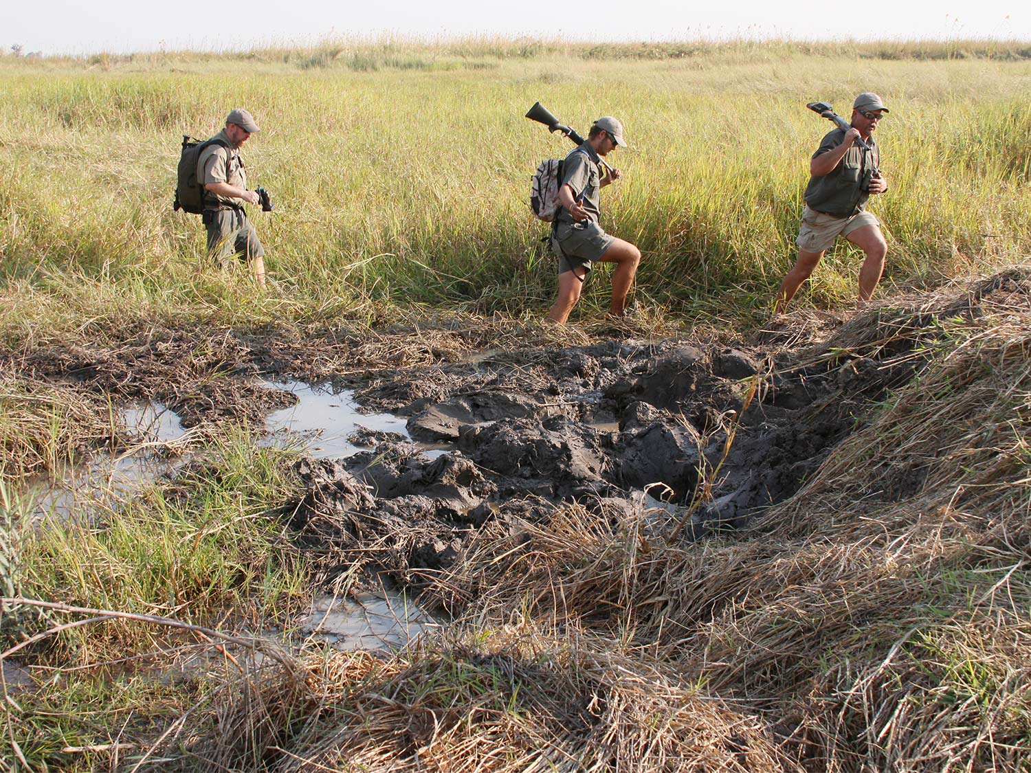 Hunters trek through the mud in Africa.